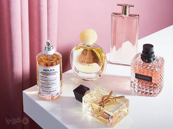 مجموعه عطرهای لوکس روی میز با تم صورتی و نور نرم